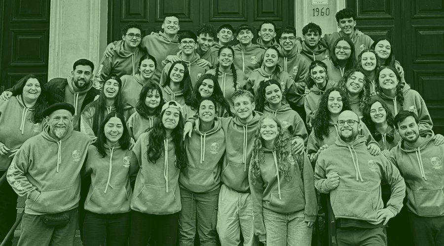 Una generación de Animadores posando con sus canguros verde claro en la escalinata del colegio.