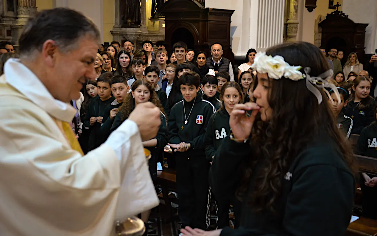 El Padre Guillermo Porras le da la Primera Comunión a una de las alumnas de los Cuartos años.